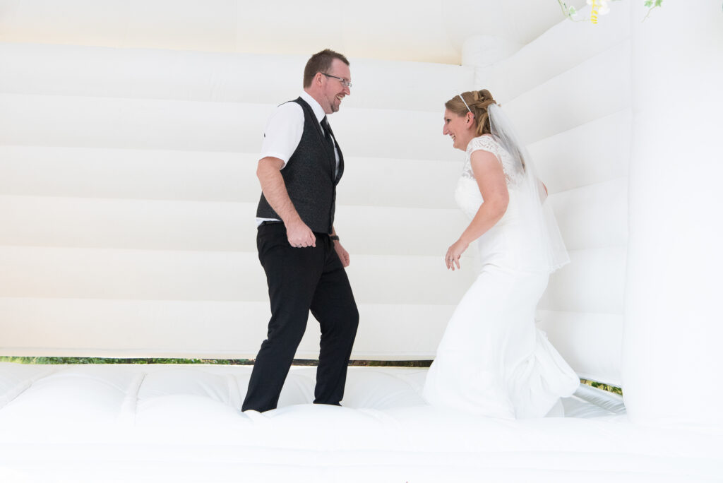 Das frische gebackenen Brautpaar ist in einer weißen Hüpfburg und hüpft.
Hochzeitsfotografen