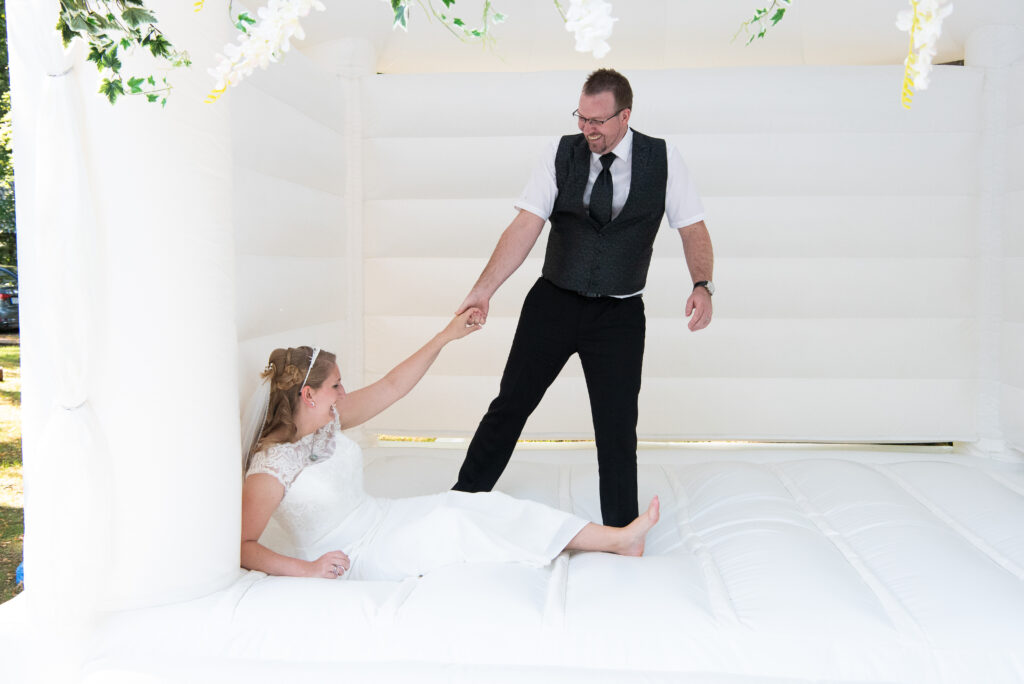 Beim Hüpfen in der weißen Hüpfburg ist die Baut gefallen, der Bräutigam reicht ihr die Hand
Hochzeitsfotografen